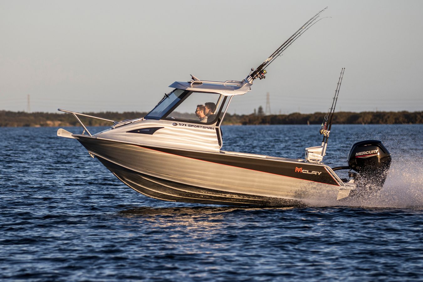 Mclay Sportsman 571 HT anchored with a black boat engine crossing in a shallow water