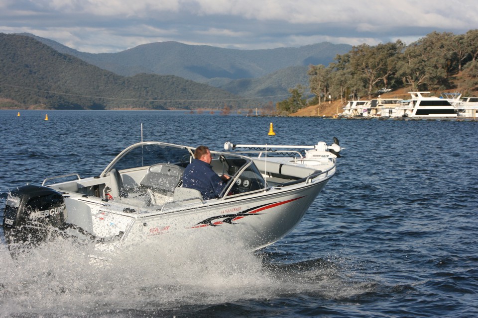 503 Wanderer Silver boat speeds, stern motor churning white spray.